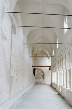 an empty hallway with white walls and arches