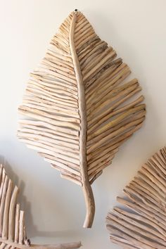 three pieces of driftwood are arranged on the wall next to each other, including one leaf