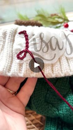 someone is stitching the word jesus on a knitted christmas stocking ornament