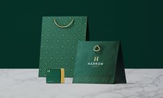 a green shopping bag with the word harrow on it next to an empty wallet