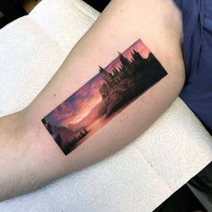 a man's arm with a castle on it and the sky in the background