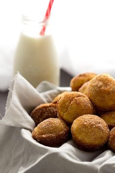 cinnamon sugar mini muffins in a basket with a glass of milk on the side