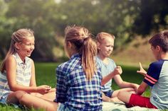 four children sitting on the grass talking to each other and having fun with each other