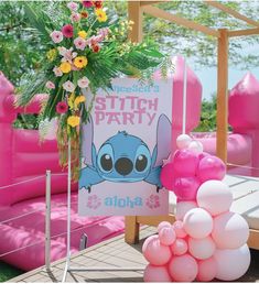 there is a sign that says stitch party next to some balloons and flowers on the ground