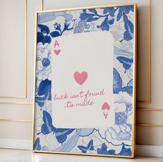 a blue and white playing card with pink hearts on it, sitting in front of a wall