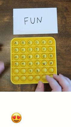 a person holding a yellow plastic keyboard with the word fun written on it next to a paper that says fun