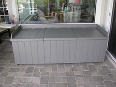 a large gray bench sitting in front of a window on the side of a building