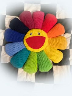 a multicolored knitted flower sitting on top of a checkered table cloth