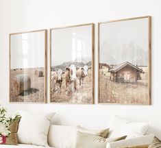 three framed pictures hang on the wall above a couch in a living room with white furniture