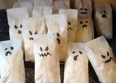 many bags with faces drawn on them are sitting on the counter in front of each other