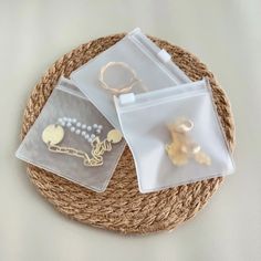 three clear bags with gold charms in them on top of a roped place mat