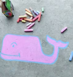 some crayons are laying on the ground next to a drawing of a whale