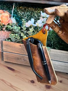 a pen holder hanging from the side of a wooden bench