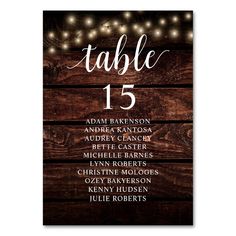 the rustic wood table number sign is shown with string lights