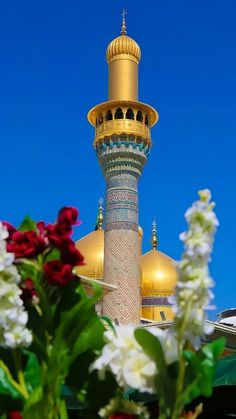 flowers are in front of a tall building with gold domes on the top and sides