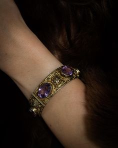 A magnificent antique piece that's steeped in Victorian history.  This one-of-a-kind piece features six stunning amethysts totaling an impressive 48 carats. It's set in a gorgeous gold-gilt setting with intricate detailing and fretwork, complete with a secure tube and pin clasp and an added safety chain for extra security. Weighs 59 grams (2.1 oz) Width 20mm across 2.5 inch bracelet which will fit a 6.5 - 7 inch wrist Amethysts measure 12mm down x 17mm across Please look at all the pictures and contact us if you have any questions. Thanks for visiting our store🤎 Follow us on Instagram @heritagehouse.finds for the latest vintage finds and styling tips! Victorian Bracelet Antique, Victorian History, Amethyst Bangle, Victorian Bracelet, Bangle Gold, Doll Jewelry, Safety Chain, Styling Tips, Antique Victorian