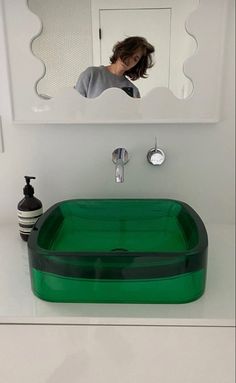 a woman taking a selfie in front of a bathroom mirror with a green sink