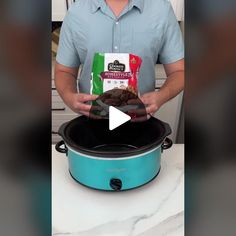 a man holding a bag of cookies in front of an electric crock pot with the lid open