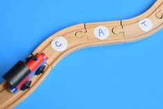 a wooden toy train with the word cat on it's track and two cars