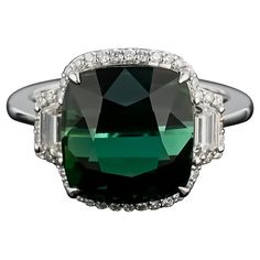 An elegant and simple cocktail ring using a 9.26 carat cushion cut Tourmaline centre stone, with 0.37 carat trapeze Diamond side stones and 0.26 carat brilliant cut diamonds sorrounding it, all set in 18K white and gold. The center stone has an ideal green color, with no inclusions and is completely transparent. The cut of the stone makes it look like a cats-eye, hence making it a very unique stone. Currently a ring size US 7, but we can resize the ring for you without additional cost Certificat Simple Cocktail, Modern Engagement Rings, Gold Cocktail Ring, Gold Cocktail, Diamond Cocktail Rings, Tourmaline Stone, Cats Eye, Modern Ring, Tourmaline Ring