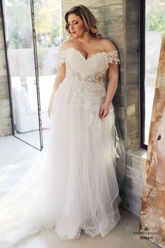 a woman in a wedding dress leaning against a wall