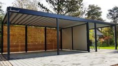 an outdoor covered area in the middle of a park with trees and bushes behind it