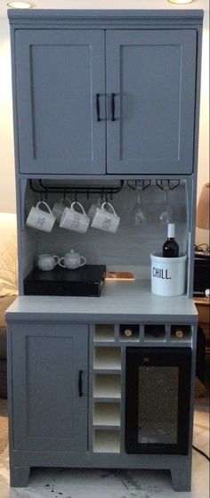 a grey cabinet with wine glasses and cups on the top, next to a coffee maker