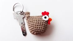 a crocheted keychain with a chicken on it's side and a pair of keys in the other hand