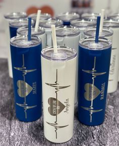 several cups with straws are lined up on a table together, one is blue and the other is white