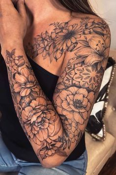 a woman's arm with flowers on it and her hand resting against her face