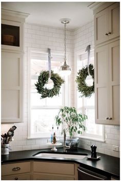 two wreaths hanging over a kitchen sink