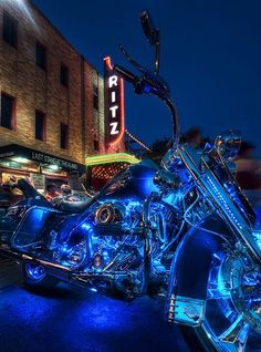 a blue motorcycle parked on the side of a road next to a tall brick building