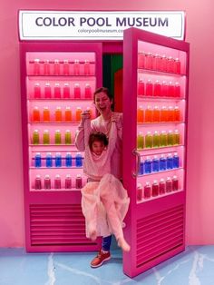 a woman and child standing in front of a pink display case with lots of products on it