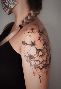 a woman's shoulder tattoo with flowers and laces on the top of her arm