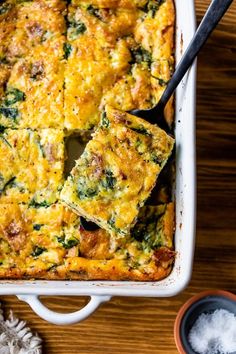 a casserole dish with broccoli, cheese and other toppings on a wooden table