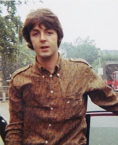 a man standing in front of a car with his hand on the door handle and looking at the camera