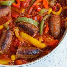 a pan filled with sausages, peppers and onions