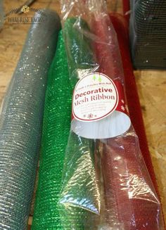 three rolls of green and red mesh sitting on top of a wooden table next to each other