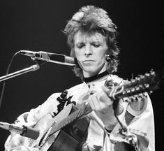 a woman playing an acoustic guitar in front of a microphone