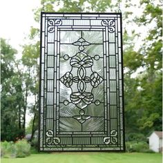 a stained glass window in the middle of a grassy area with trees and grass behind it