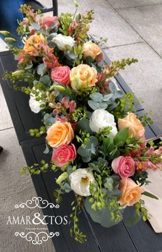 an arrangement of flowers is sitting on a bench