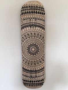 a skateboard with an intricate design on the front and back sides, hanging from a wall