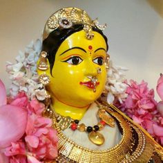 a yellow statue is surrounded by pink flowers