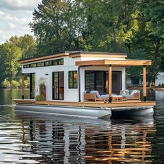 This modern houseboat features a sleek white and natural wood design with large windows and glass doors, offering stunning water views and abundant natural light. The spacious deck, furnished with cozy seating, is perfect for relaxation and outdoor entertaining. Nestled in lush greenery, this houseboat combines contemporary architecture with the tranquility of waterfront living, making it an ideal serene getaway on the water. Tiny Home Boat House, Living On The Water, House Boat Renovation, Barge Interior Houseboat Living, Lake Resort Design, Pontoon Houseboat Diy, Houseboat Aesthetic, Small House Boat, Boat House Ideas Lakes