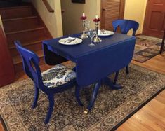 a blue table with two chairs and plates on it in front of a stair case