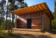 a small wooden building in the middle of a forest with lots of trees around it