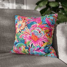 a colorful floral pillow sitting on top of a gray couch