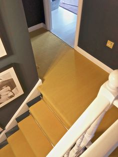 stairs leading up to an open door with pictures on the wall and carpeted floor