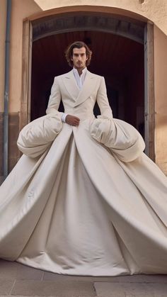 a man in a white suit and tie is standing on a giant dress made out of cloths