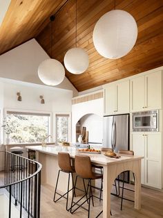 a kitchen with white cabinets and wooden ceilinging next to a spiral stair case in the center